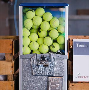 tennis balls are in an old fashioned vending machine