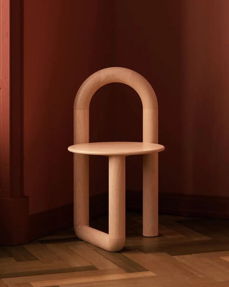 a wooden chair sitting on top of a hard wood floor next to a red wall