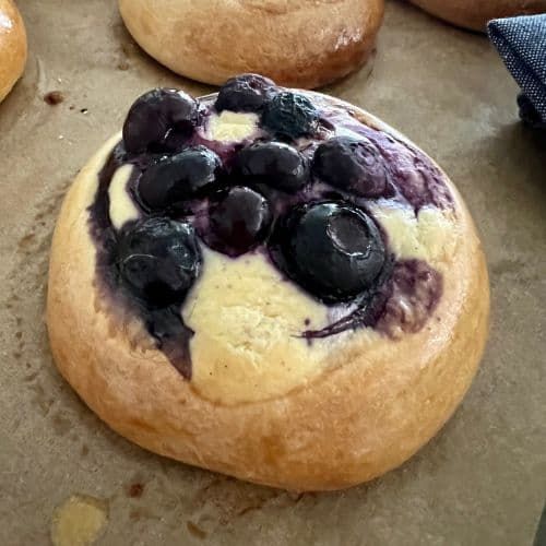 blueberries and cream are on top of some breads that have been baked in the oven