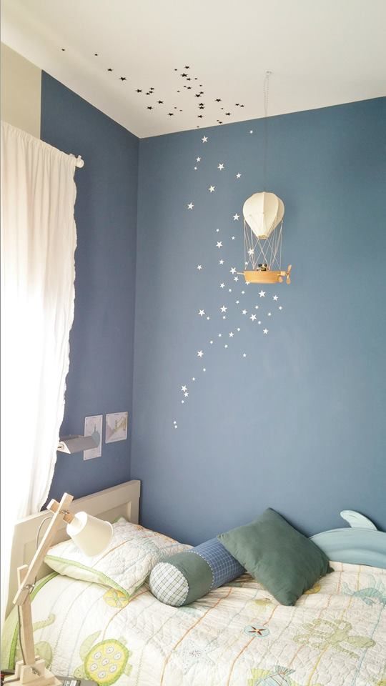 a bedroom with blue walls and white stars on the ceiling is decorated in an airplane theme