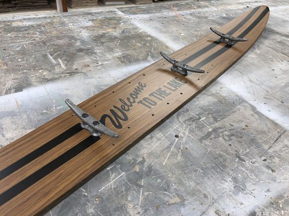 a wooden skateboard with metal straps on the top and bottom, sitting on concrete