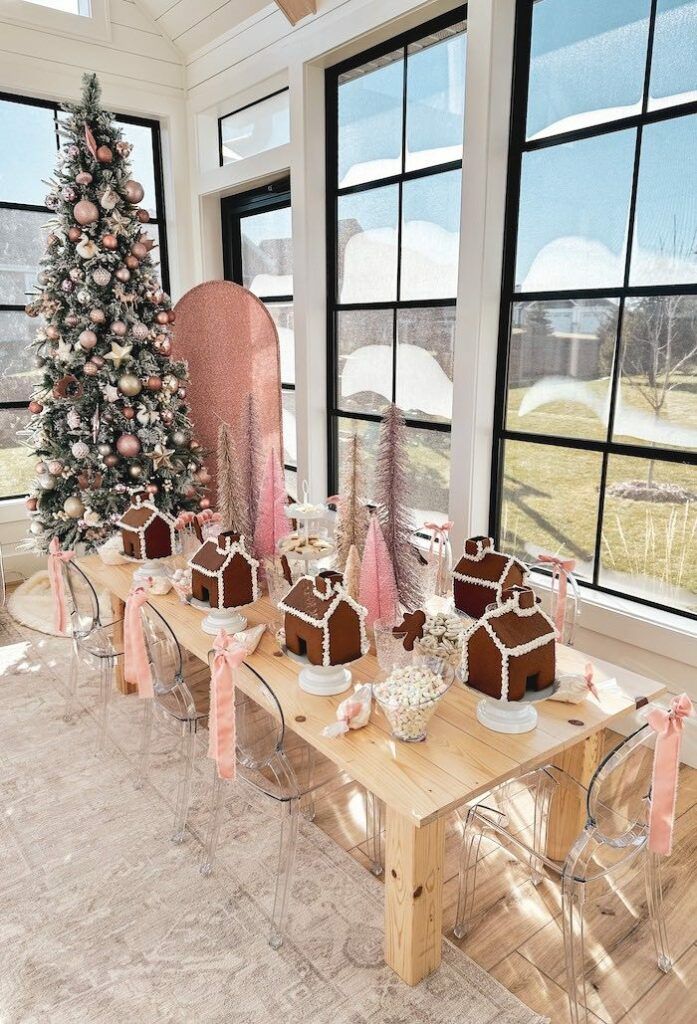 a dining room table with gingerbread houses on it and a christmas tree in the window