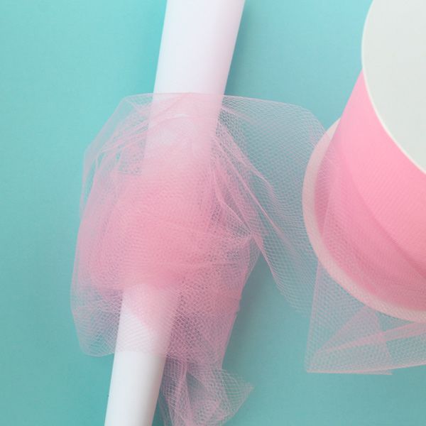 a roll of tulle sitting on top of a table next to a white cup