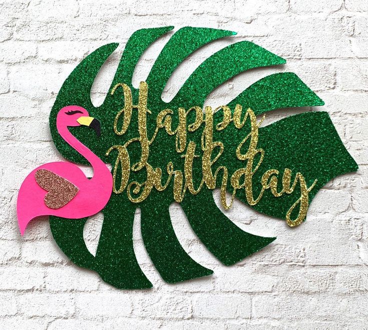 a happy birthday sign with a pink flamingo and green leaves on it's side