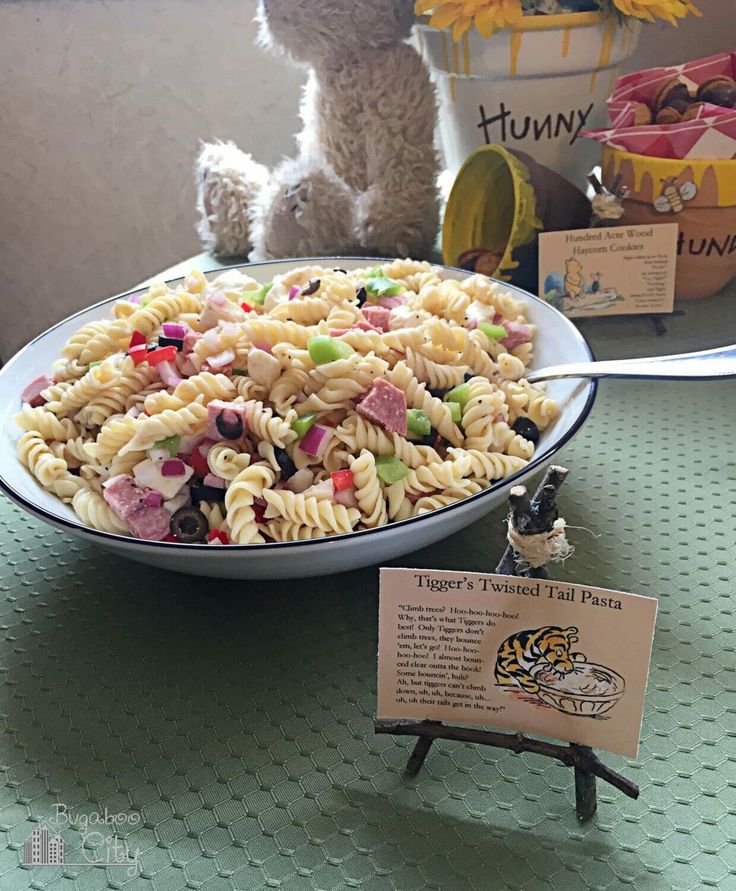 there is a bowl of pasta and a teddy bear sitting on the table next to it