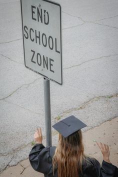 a girl in graduation gown holding up a sign that says end school zone on it