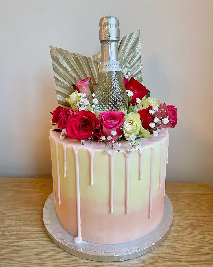 a cake decorated with flowers and a bottle of champagne sitting on top of a table