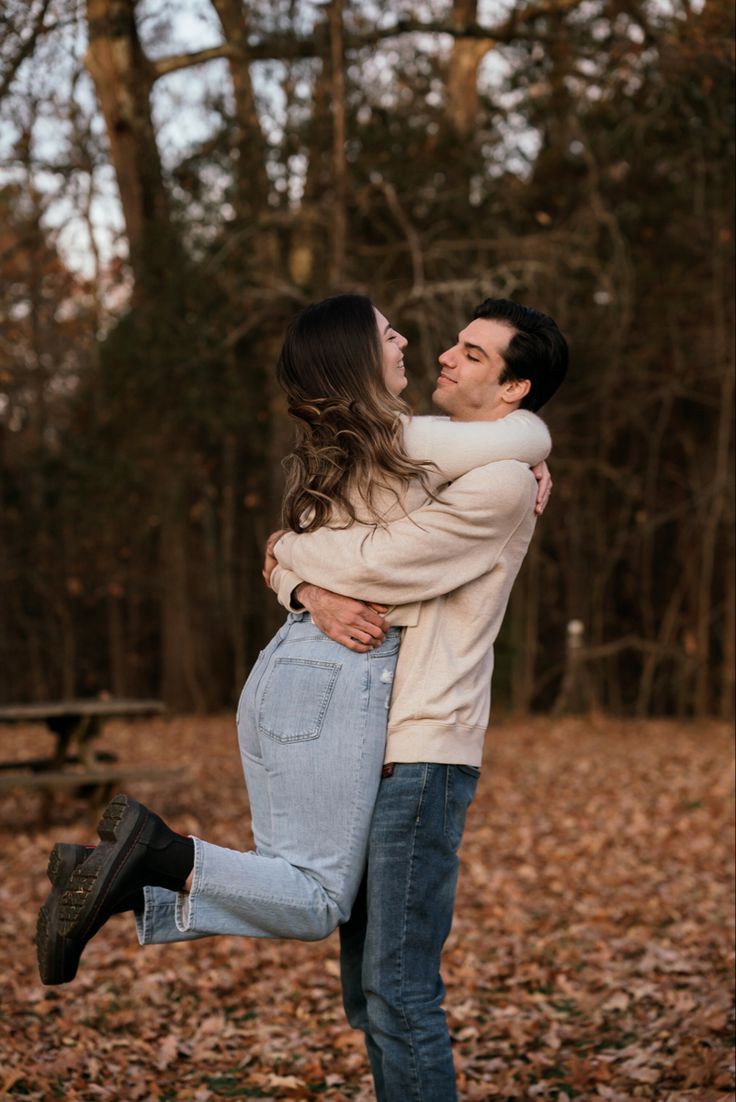 a man and woman are hugging in the leaves