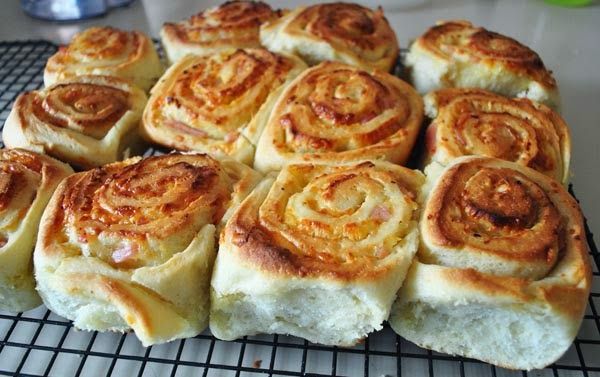 a bunch of cinnamon rolls sitting on top of a cooling rack