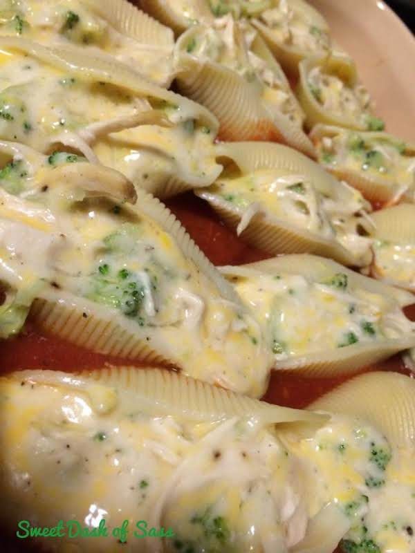 several shells covered in cheese and broccoli on a plate