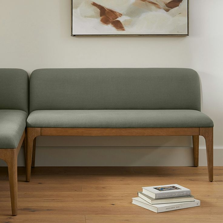 a green couch sitting on top of a hard wood floor next to a white wall