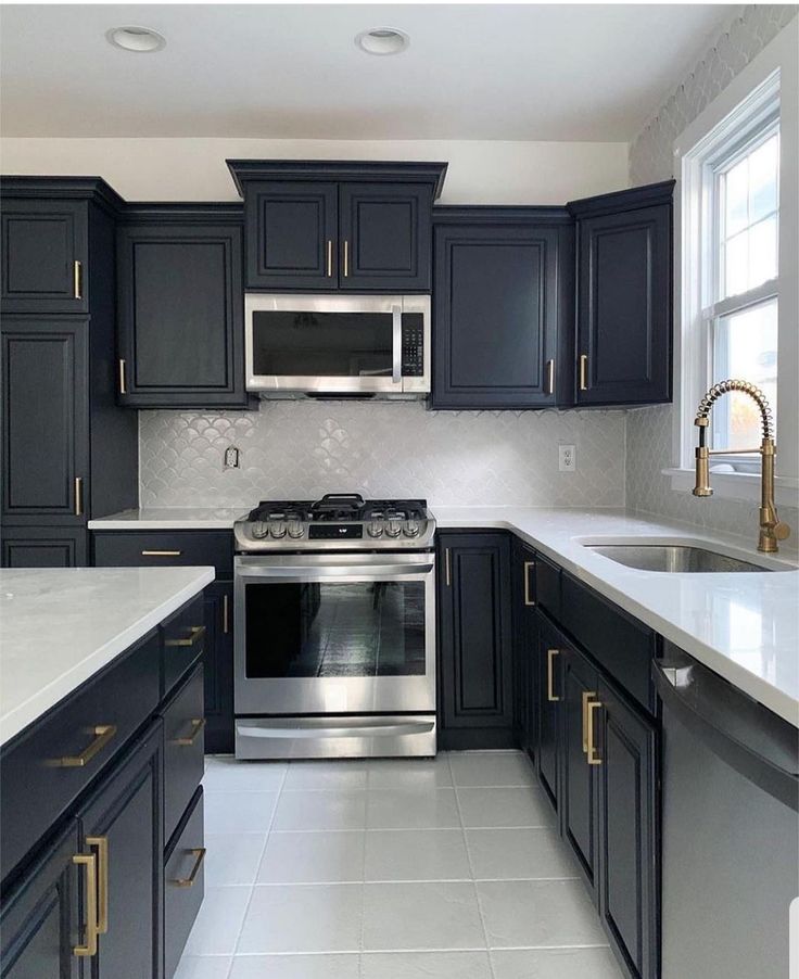 a kitchen with black cabinets and stainless steel appliances in the center, along with marble counter tops