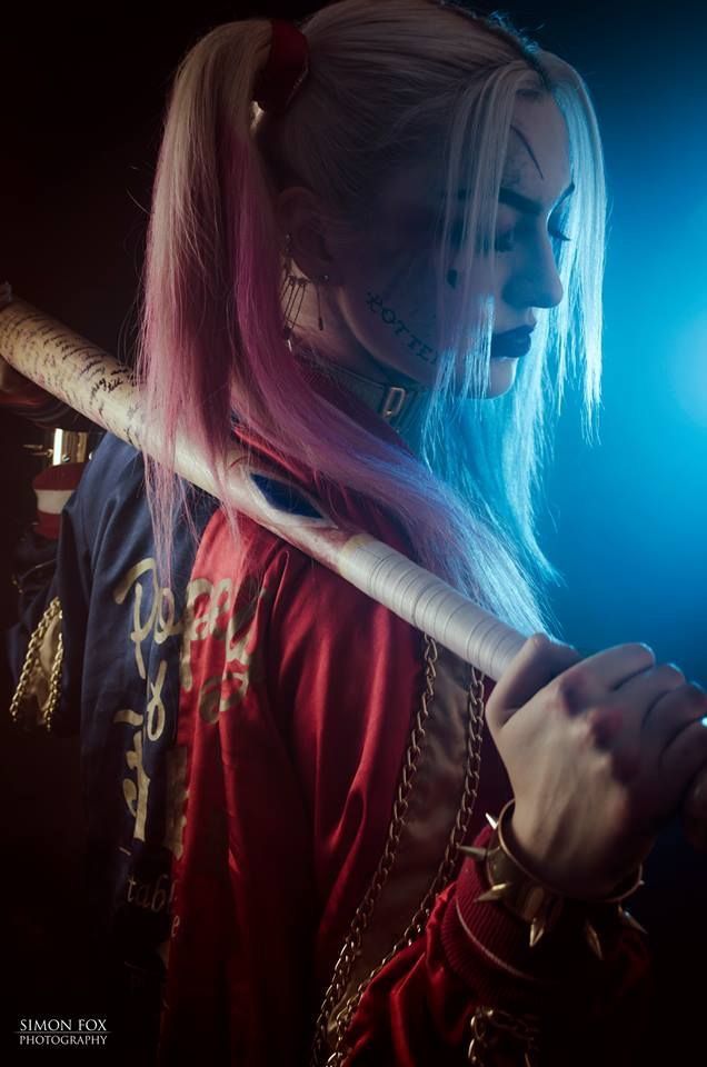 a woman with pink hair and piercings holding a baseball bat in her hand while looking down at the ground