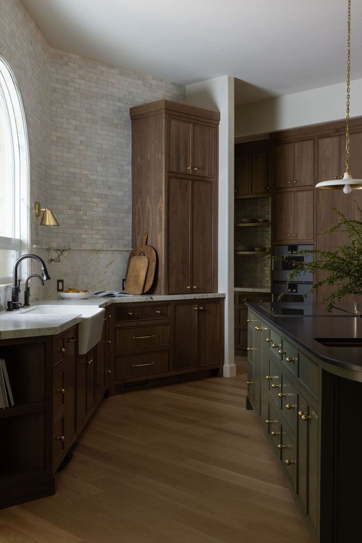 a large kitchen with wooden cabinets and an arched window above the sink, along with dark wood flooring