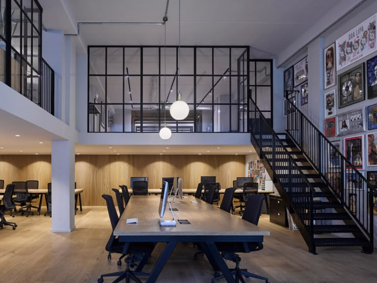 an office with wooden flooring and black railings on the walls, along with multiple tables and chairs