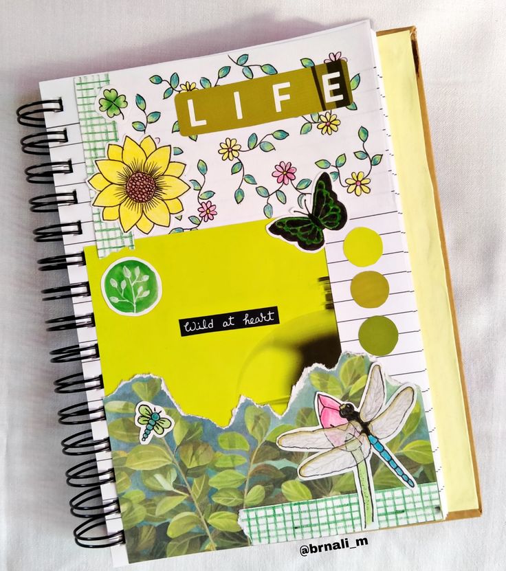 an open notebook with stickers and flowers on the cover, sitting on a white surface