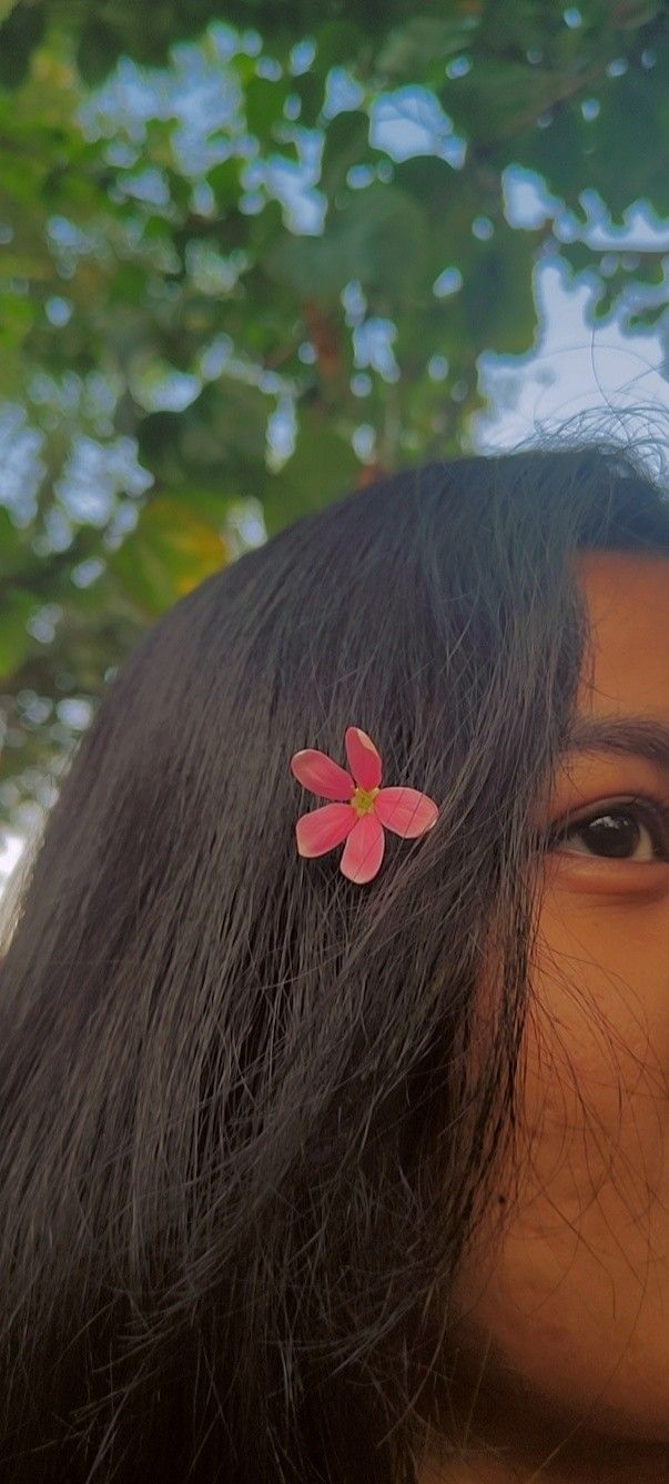 a close up of a person with long hair and a flower in the middle of her hair