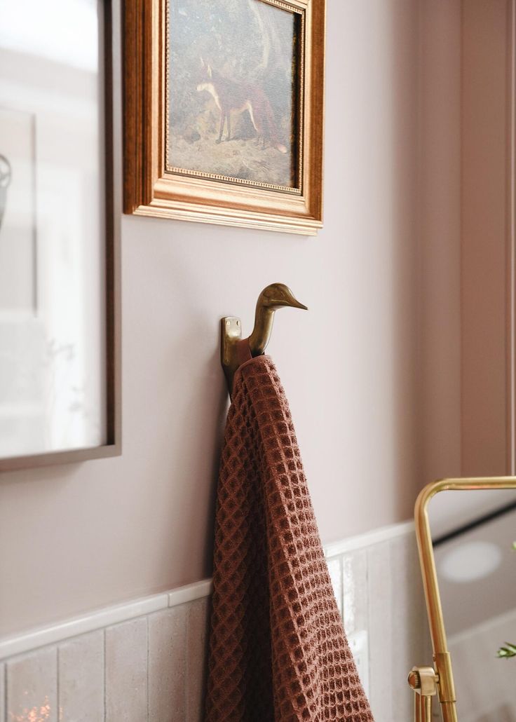 a towel hanging on the wall next to a mirror with a deer painting above it