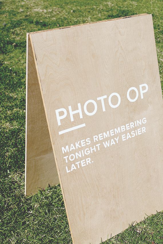 a wooden sign sitting on top of a lush green field