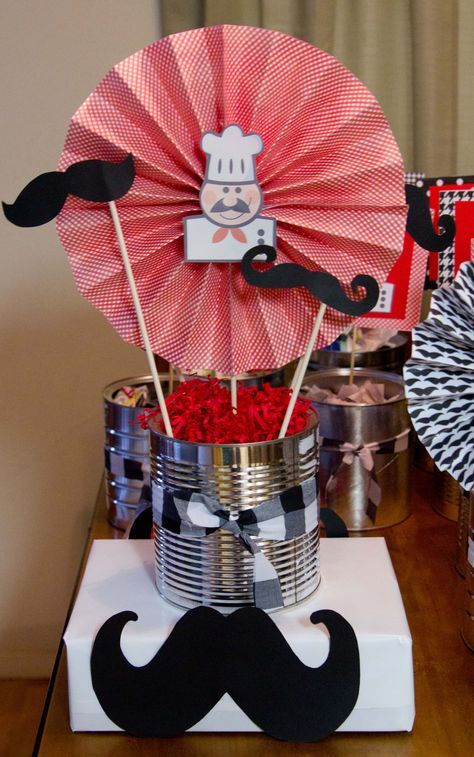 a table topped with lots of tin cans and paper flowers in the shape of mustaches