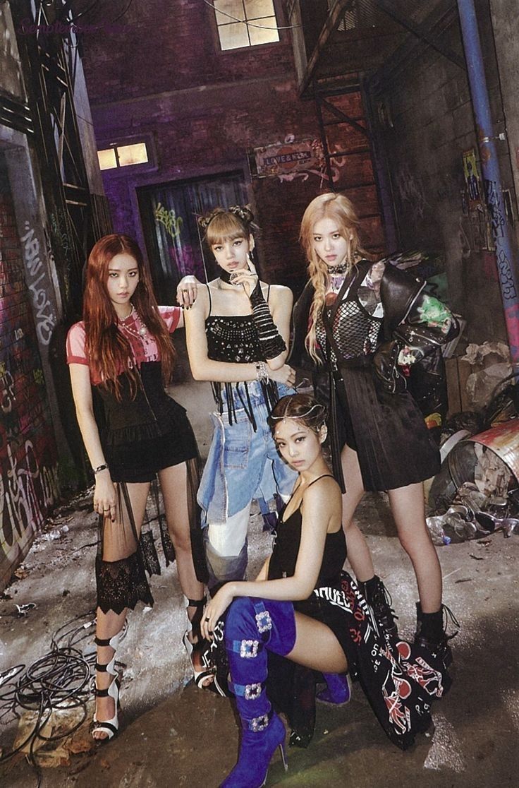 the girls are posing together in an alleyway with graffiti on the walls behind them