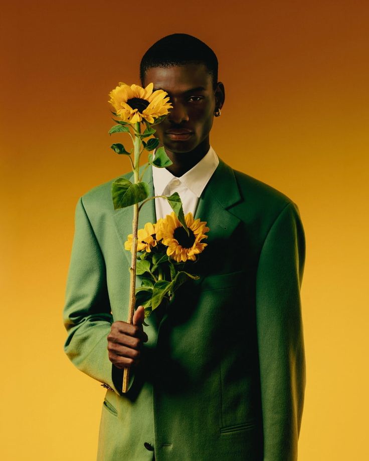 a man in a green suit holding a sunflower