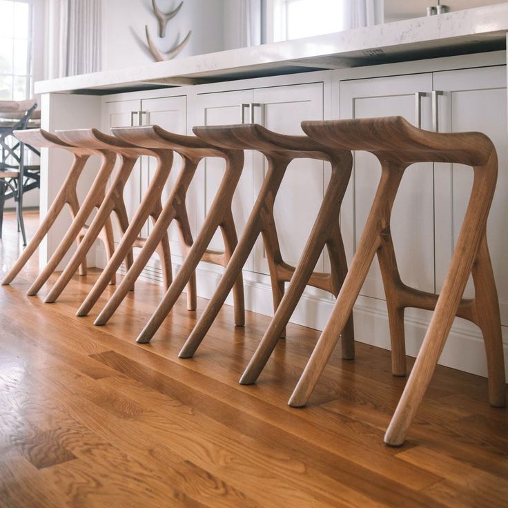 a row of wooden chairs sitting on top of a hard wood floor next to a kitchen counter