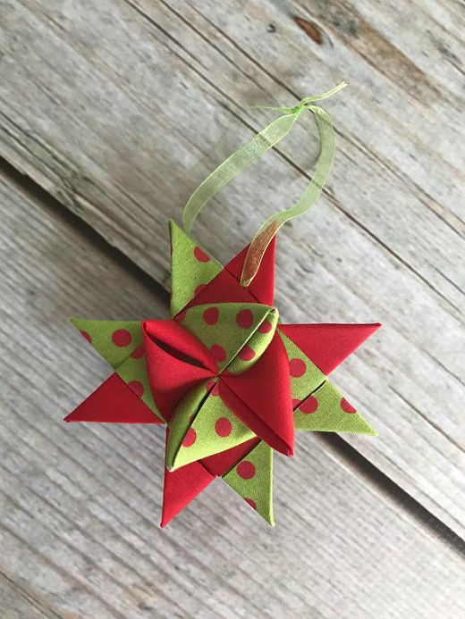 a red and green origami star hanging from a string on a wooden surface