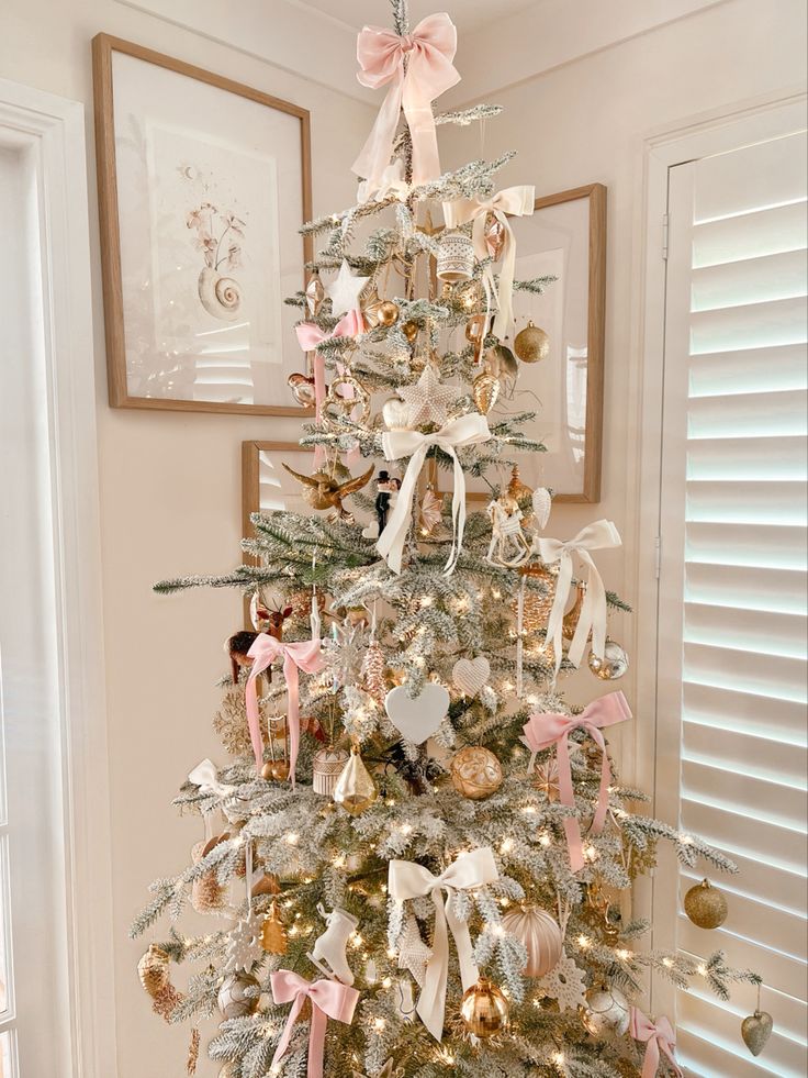 a white christmas tree decorated with pink and gold ornaments