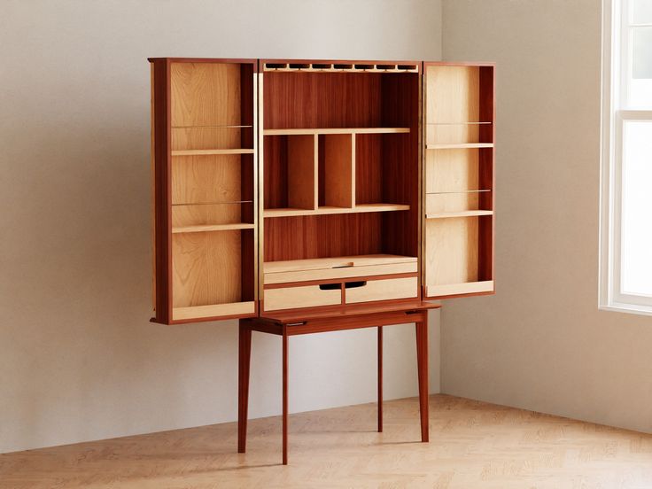 an empty room with a bookcase and desk in the corner, next to a window