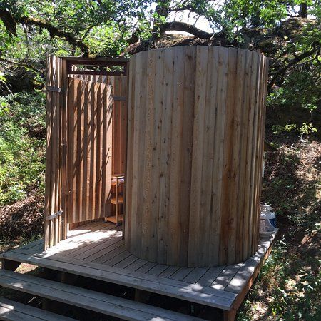 a wooden outhouse in the woods with steps leading up to it