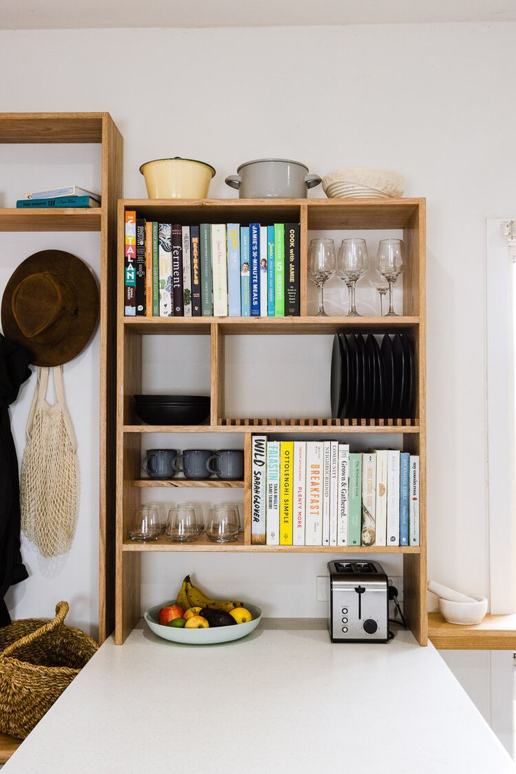 a kitchen with bookshelves, bowls and plates on the counter top in front of a window