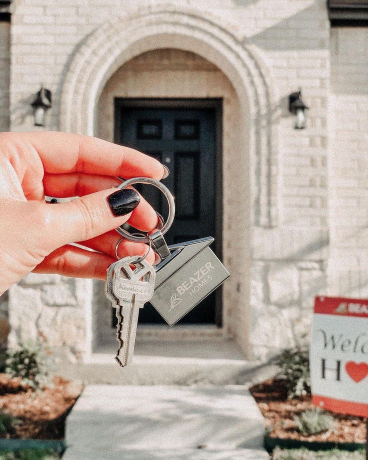 a person holding keys in front of a house