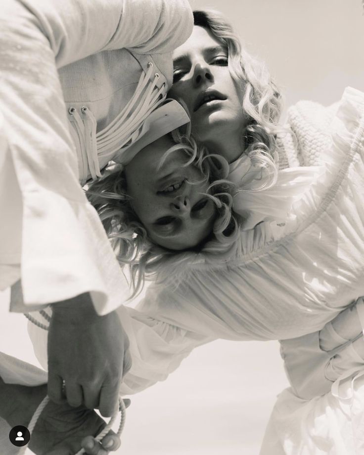 two women in white clothing are touching each other