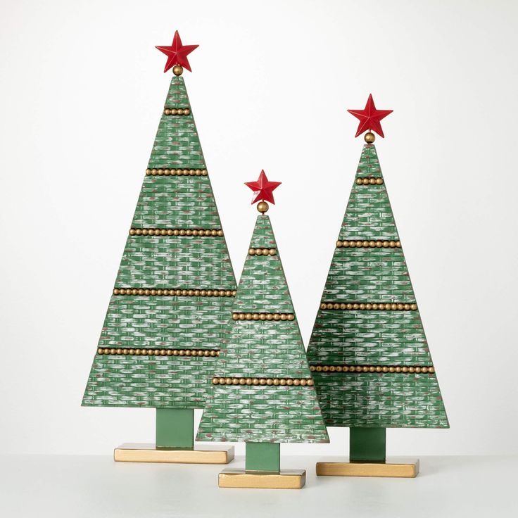 two green christmas trees with red stars on top and gold trimmings, standing next to each other in front of a white background