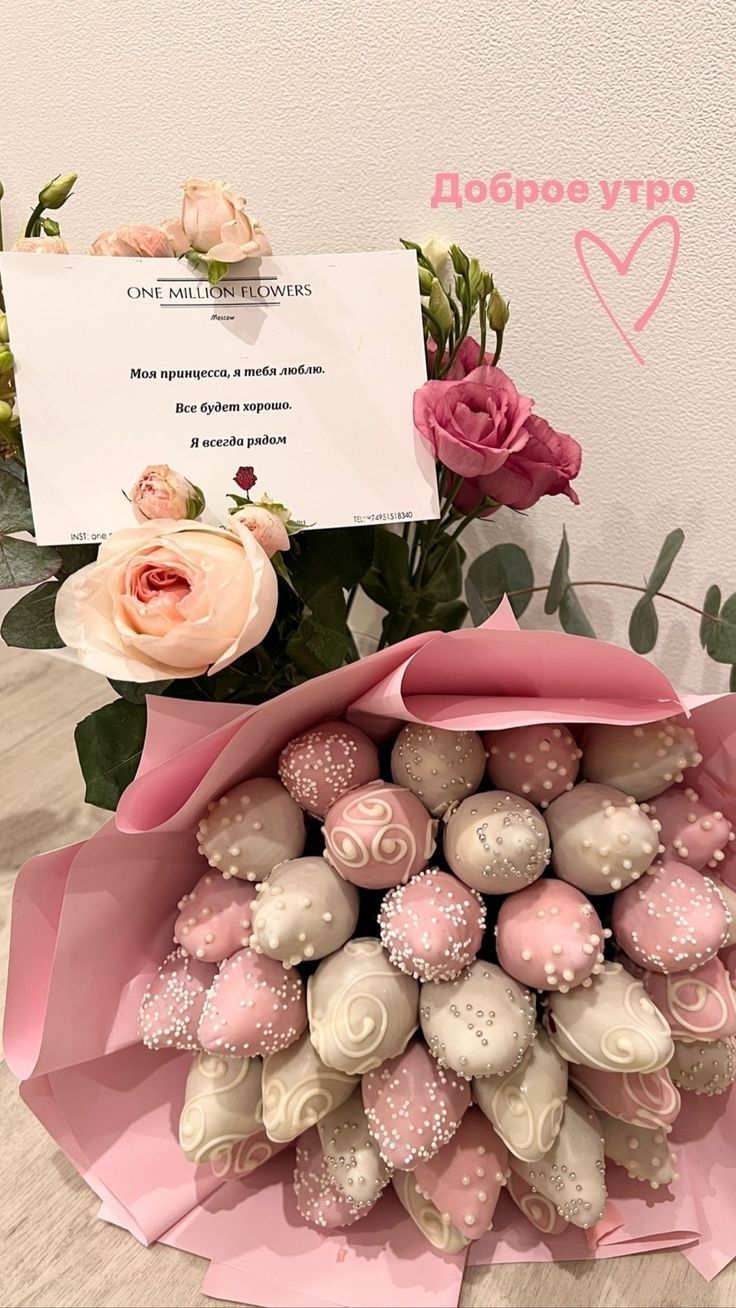 a bouquet of pink roses and white chocolates in a paper wrapper on a table