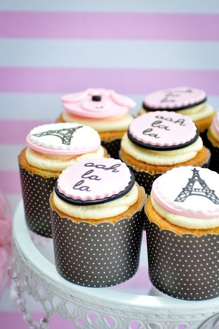 cupcakes decorated with pink and black icing on a cake plate