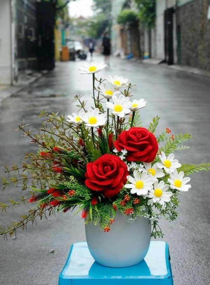 a vase filled with red roses and white daisies on top of a blue table