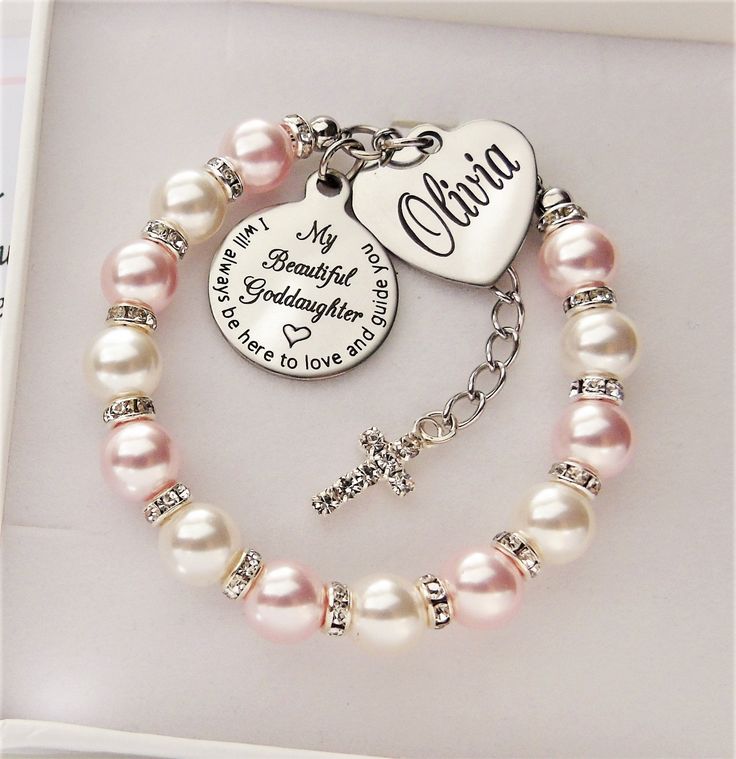 a pink pearl bracelet with a heart charm and personalized charm on it's side