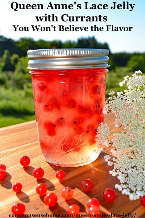 a jar filled with red berries sitting on top of a wooden table next to flowers