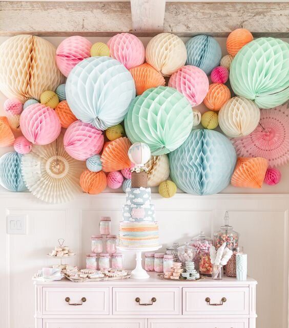 a table topped with lots of different colored paper balls on top of a white dresser