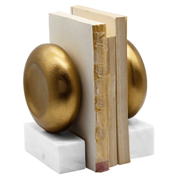 a bookend with a golden ball on it and a white block in the foreground