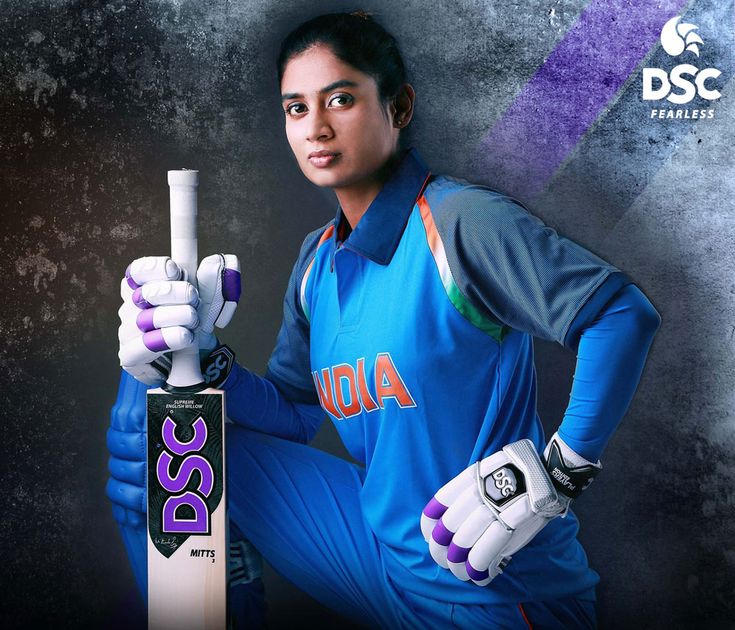 a female cricket player holding a bat and ball in one hand while posing for the camera