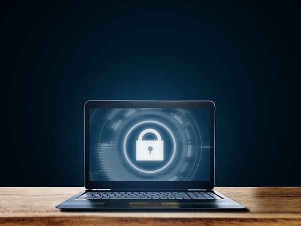 an open laptop computer sitting on top of a wooden desk with a padlock in front of it