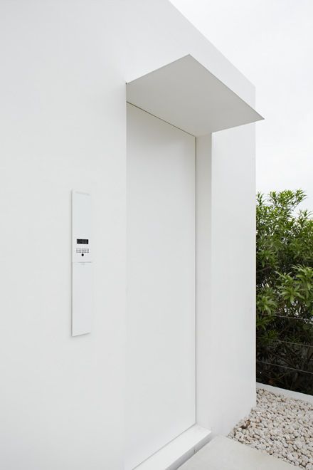 an open door to a white room with rocks on the ground and trees in the background