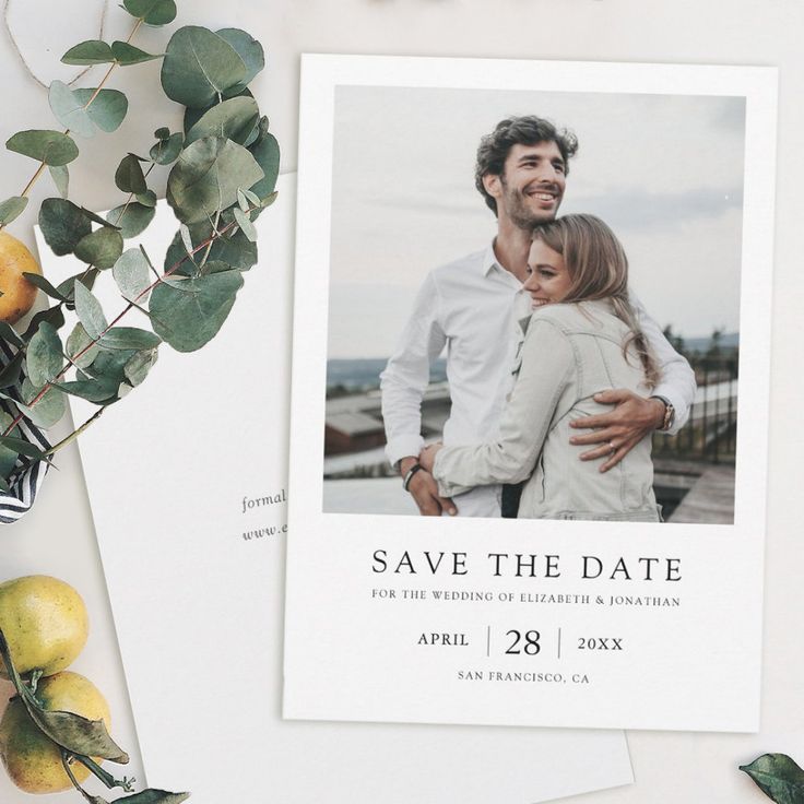 save the date card with lemons and greenery next to it on a table