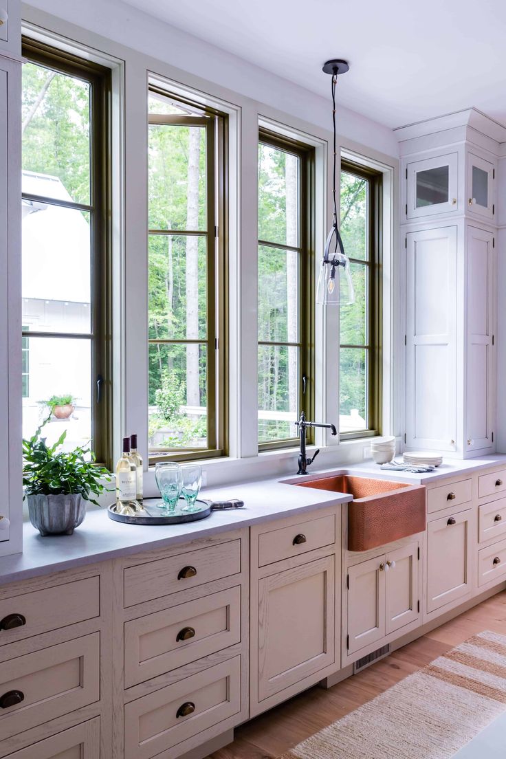 a kitchen with white cabinets and large windows