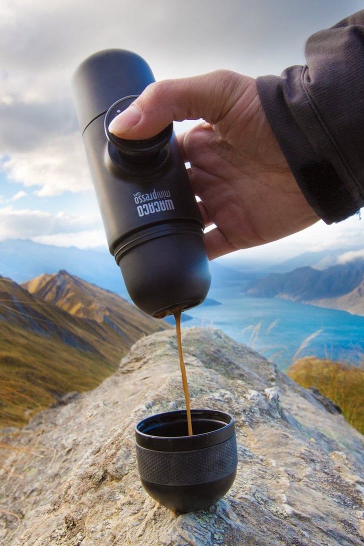 a hand holding a coffee mug with the words shop now on it and an image of mountains in the background