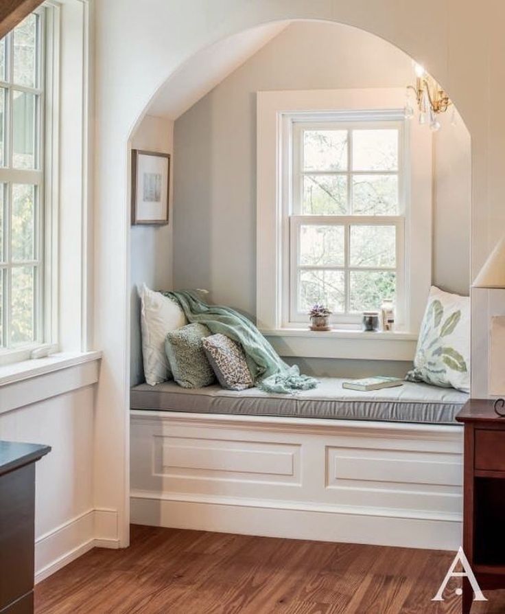 a window seat in the corner of a room with wood flooring and white walls