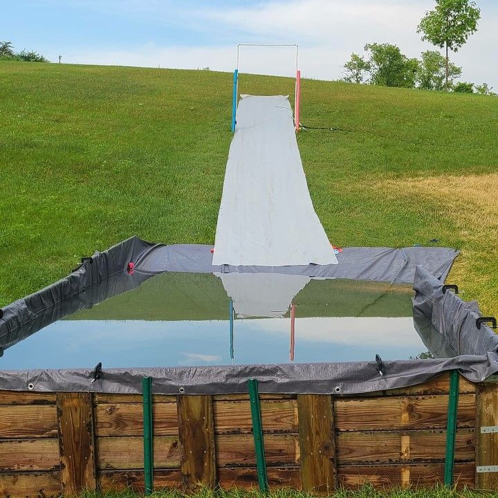 an inflatable water slide is being built into the ground with tarps on it